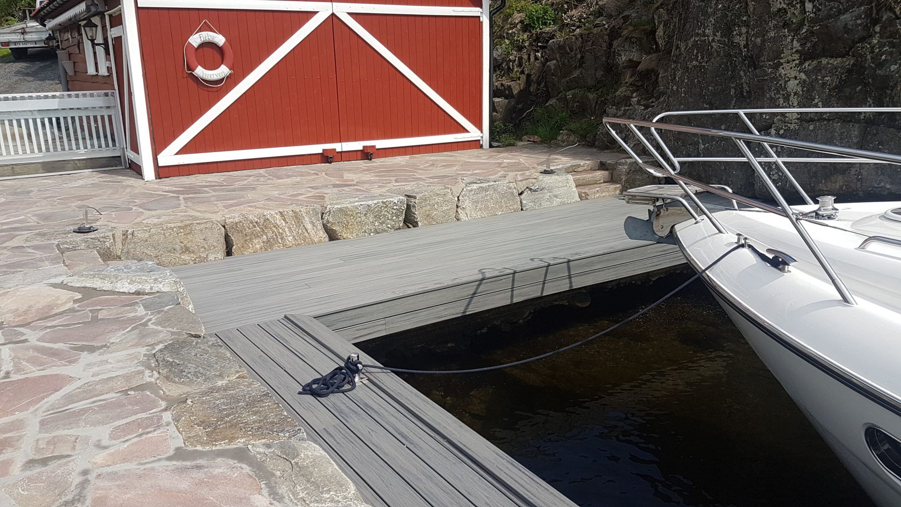 Brygge med tredekke og natursteinskant ved en båt