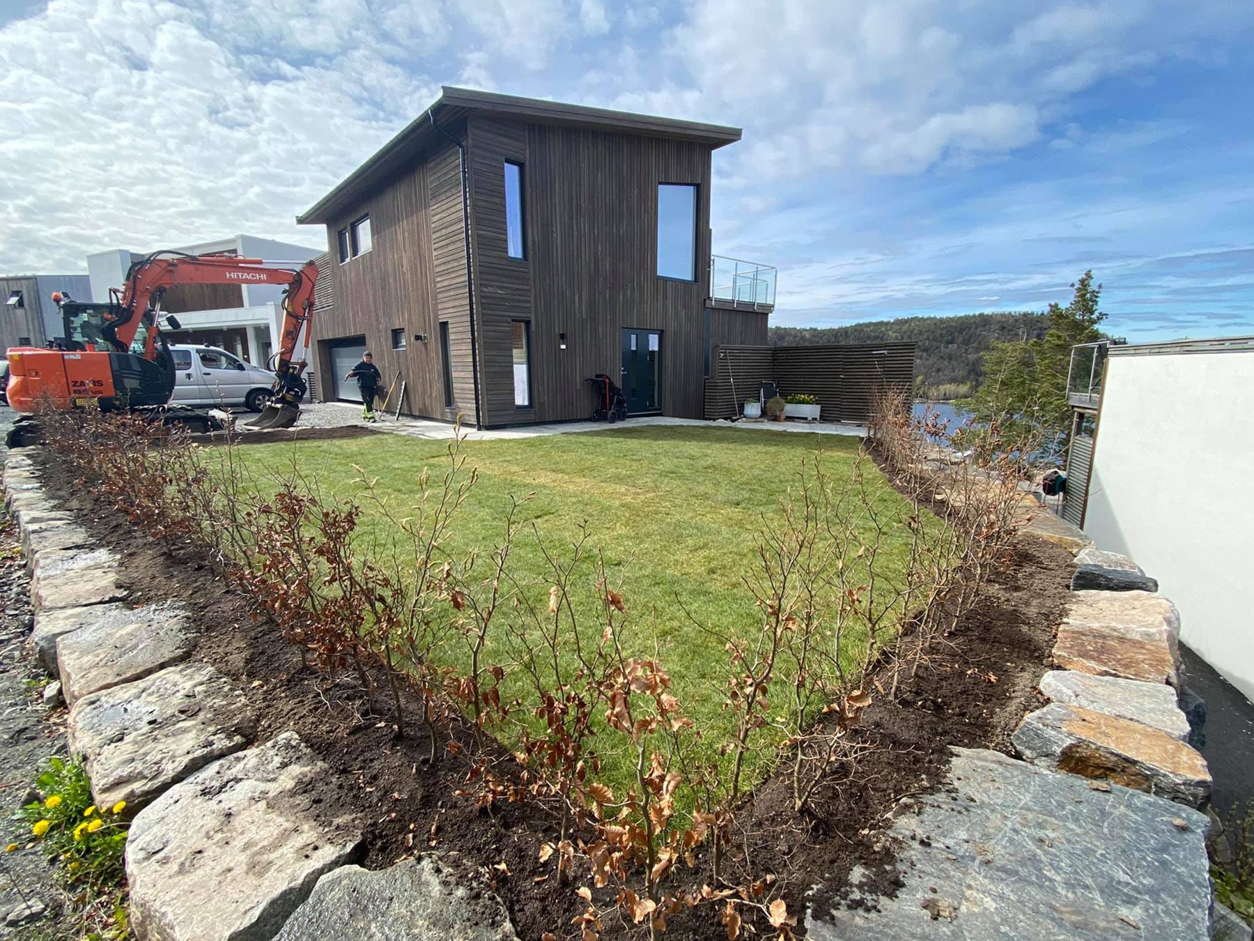 Nyanlagt plen med natursteinskant foran et nytt hus