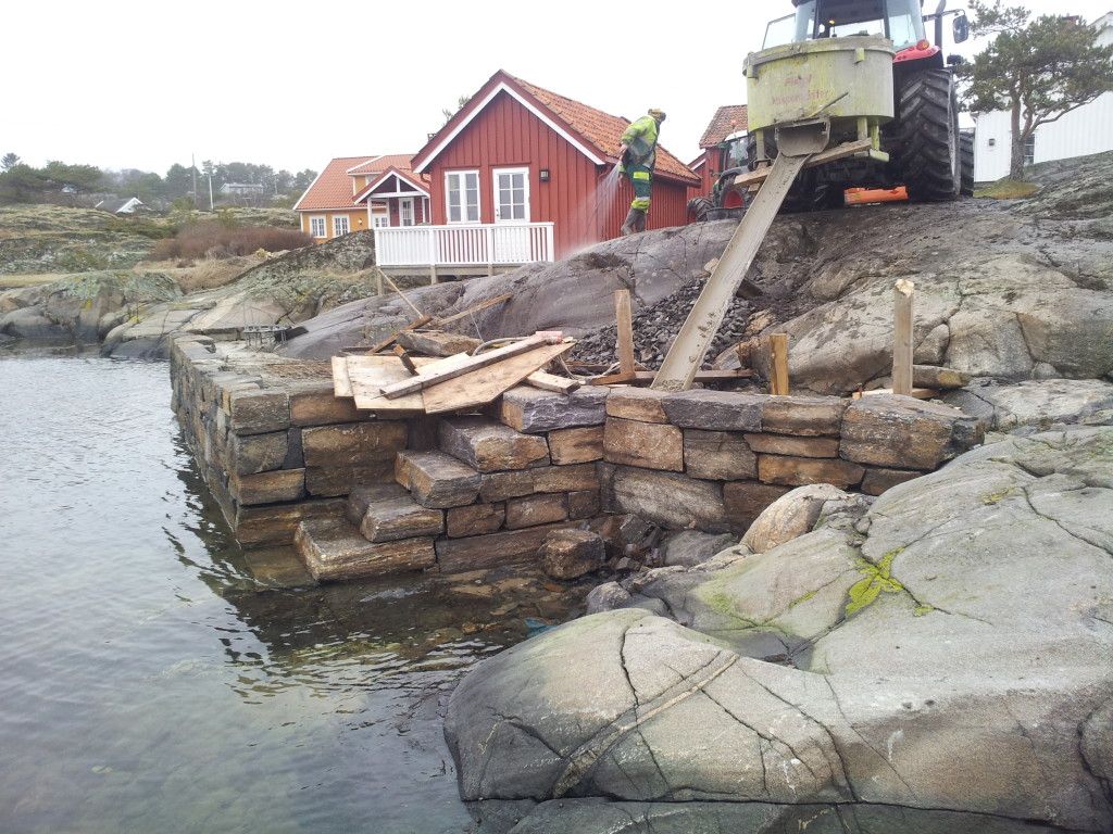 Natursteinsbrygge under bygging ved sjøen